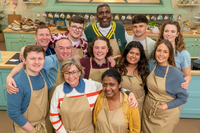 The contestants of Great British Bake Off standing together, looking into camera