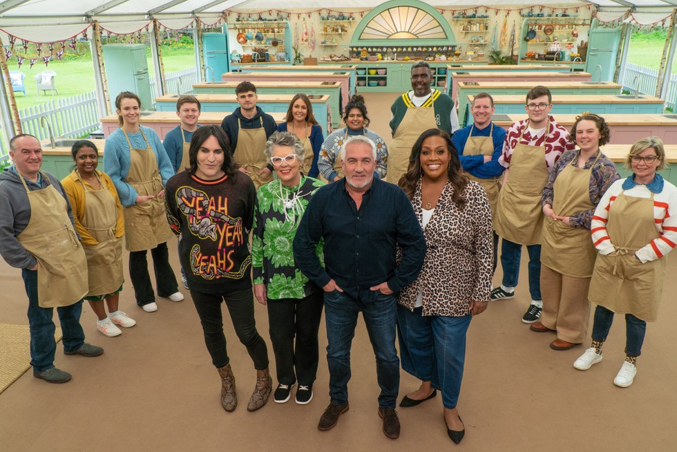 The presenters and contestants of Great British Bake Off in the tent, looking into camera