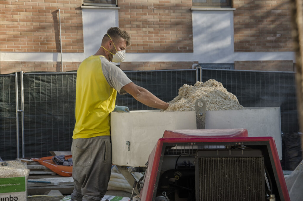 Cascina, Italy - November 06, 2015: Mason with mask mixing lime and hemp.