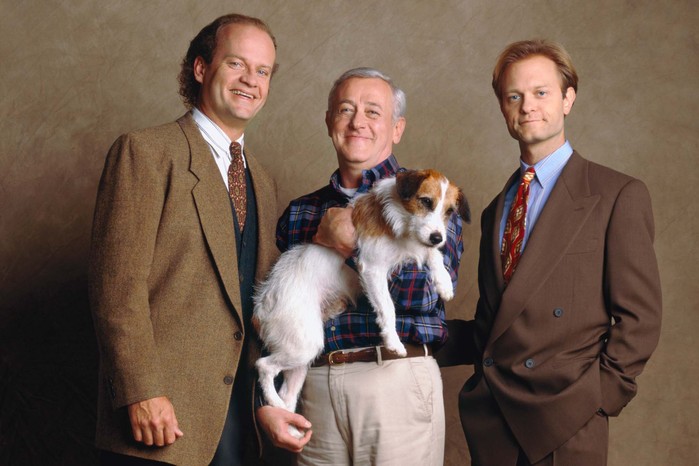 Kelsey Grammer, John Mahoney and David Hyde Pierce stand side-by-side, smiling, with John also carrying a small dog
