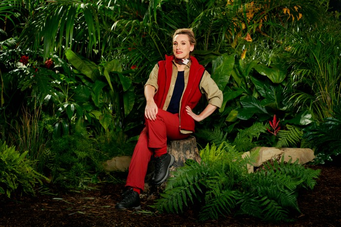 I'm a Celebrity 2023 contestant Grace Dent wearing her camp gear while sitting on a log in front of some trees ahead of the 2023 season.