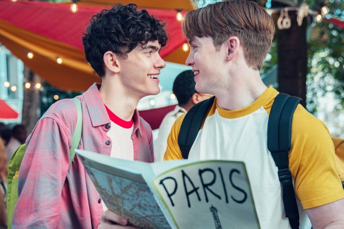 Nick and Charlie looking into one another's eyes, with a Paris guidebook in shot