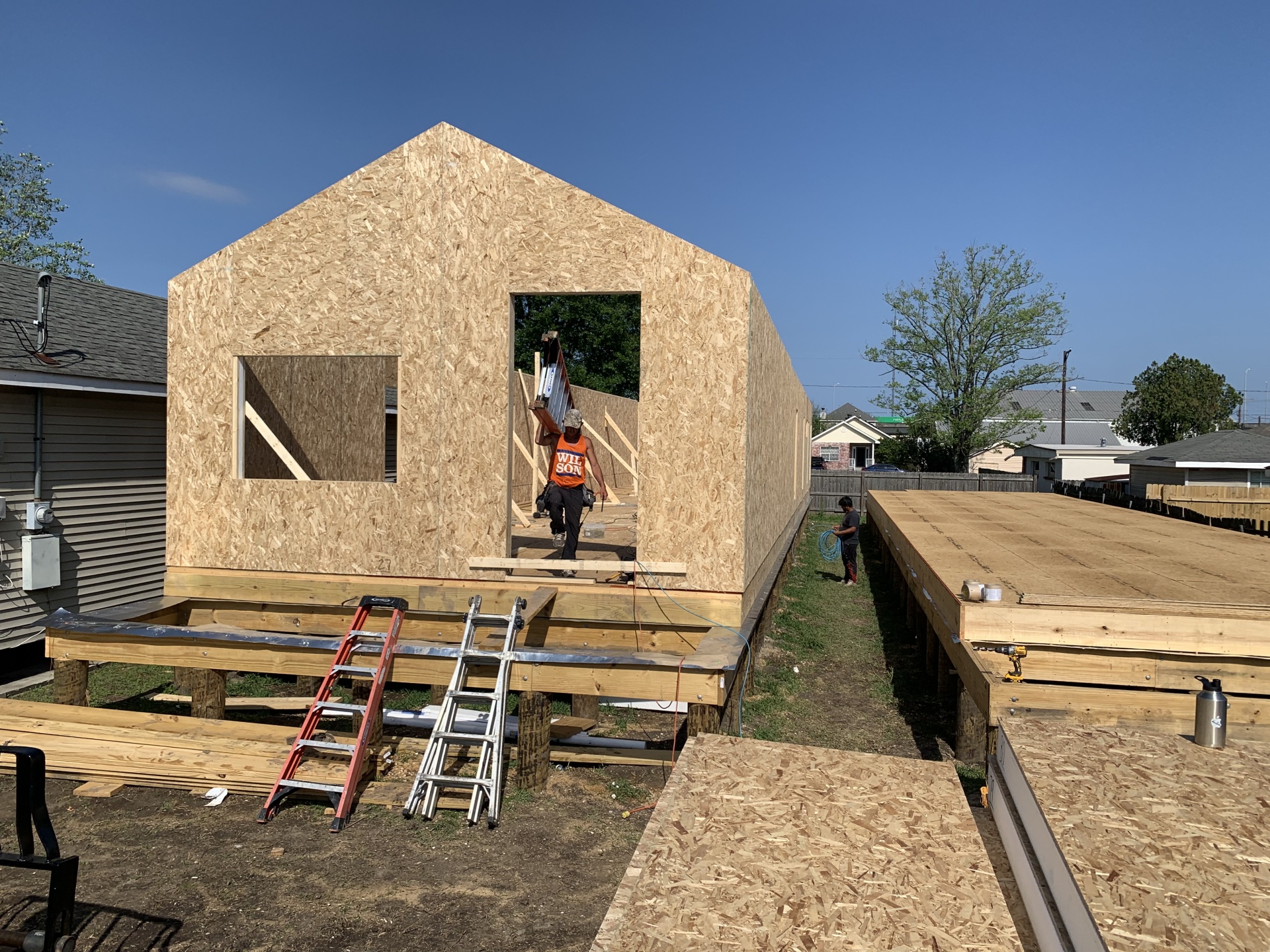 exterior view home under construction: SIPs exterior framing is erect and additional SIP panels lie adjacent, ready for installation; construction workers laboring - photo