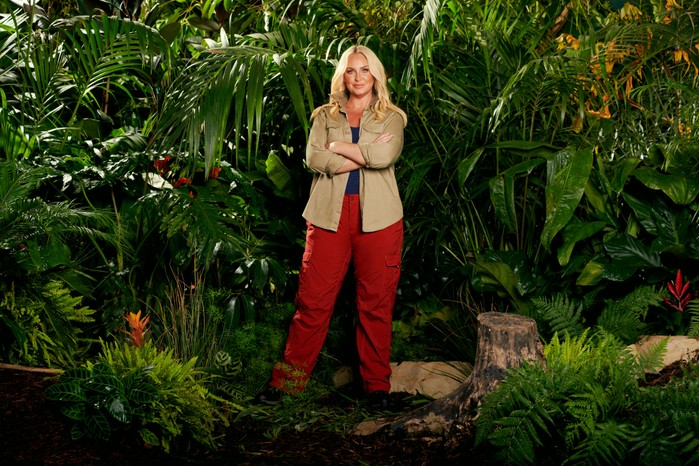 Josie Gibson wearing a khaki shirt and red trousers while posing in front of some bushes ahead of I'm a Celebrity 2023.